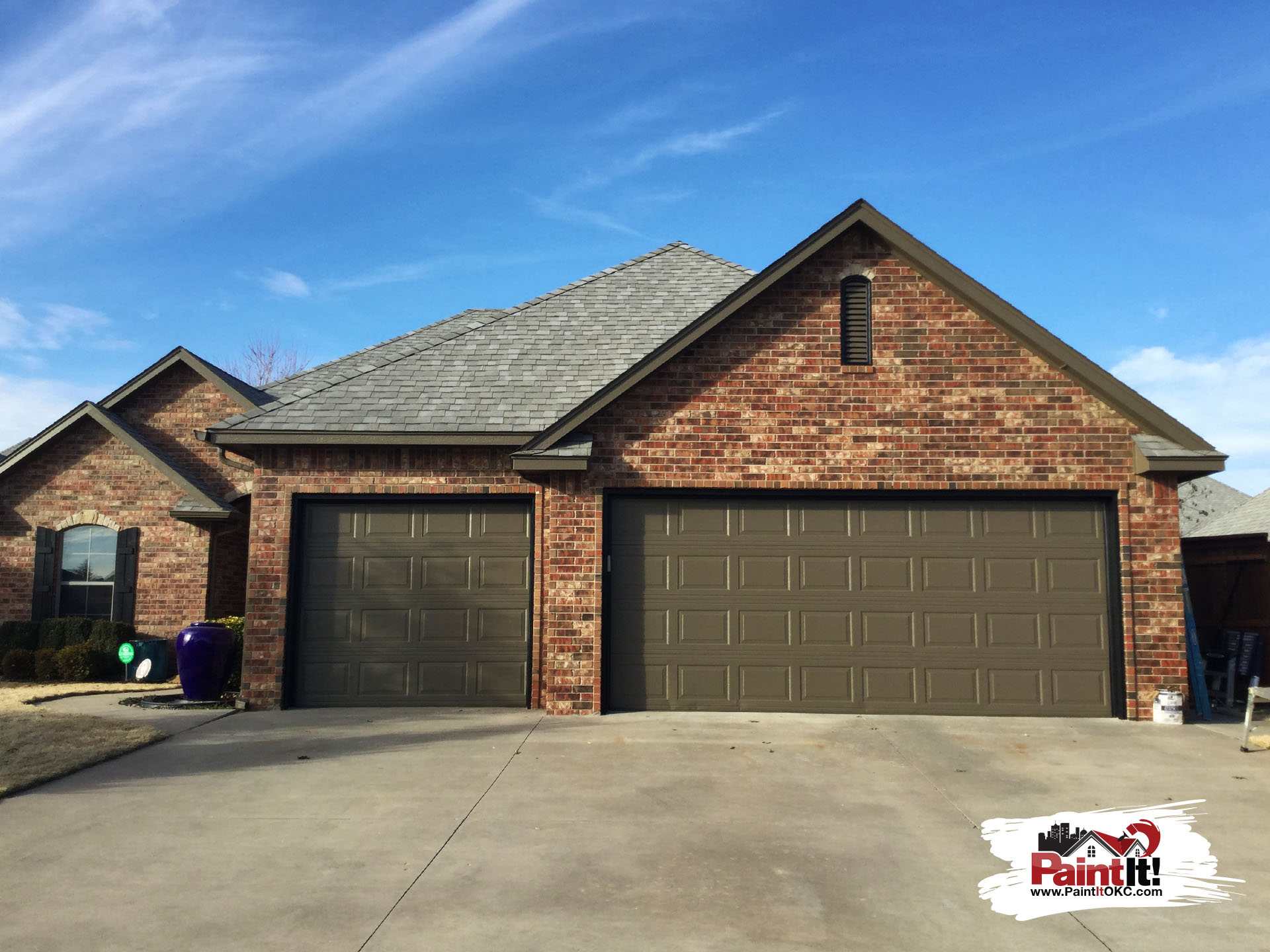 a newly painted brown garage attached to a brick house in oklahoma
