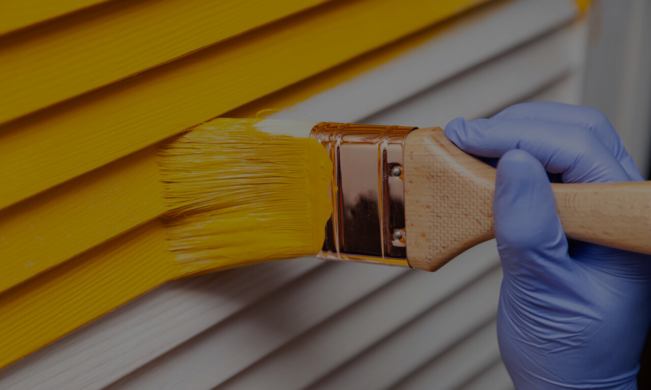 close up of painter painting a house orange