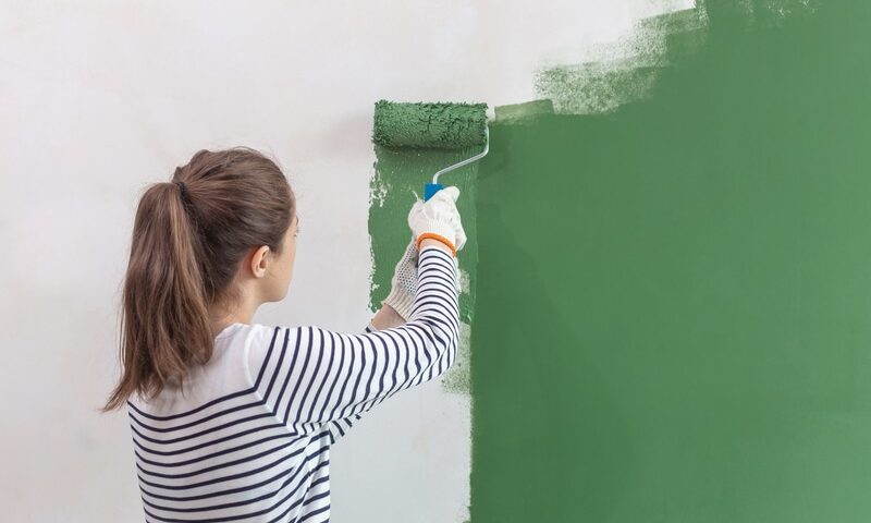 woman painting a wall green